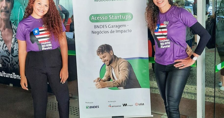 Equipe da Ela Faz ao lado do banner do BNDES