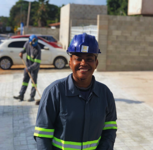 Mulher negra vestindo equipamentos de segurança sorri em canteiro de obras